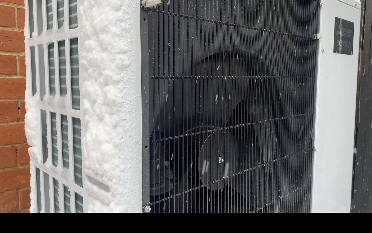 Unité extérieure de pompe à chaleur en fonctionnement sous la neige, pendant une chute de neige